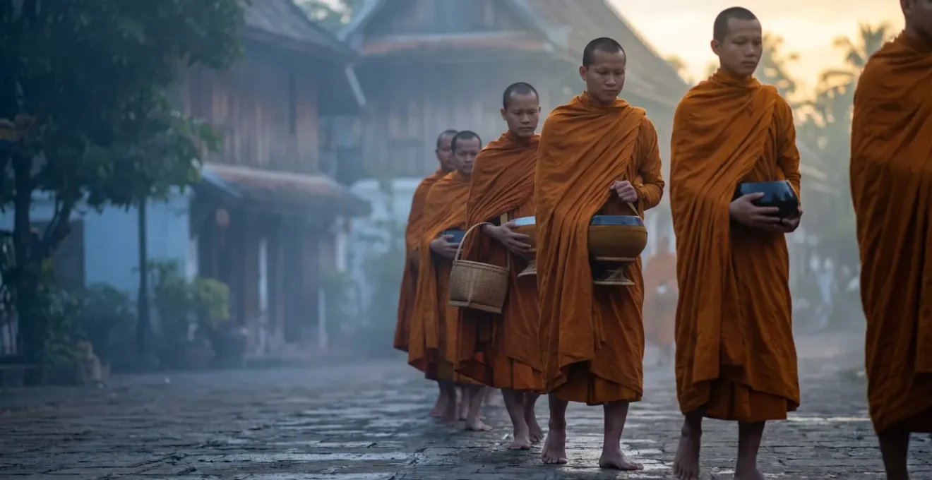 Procession silencieuse de moines à l'aurore dans les rues calmes de Luang Prabang