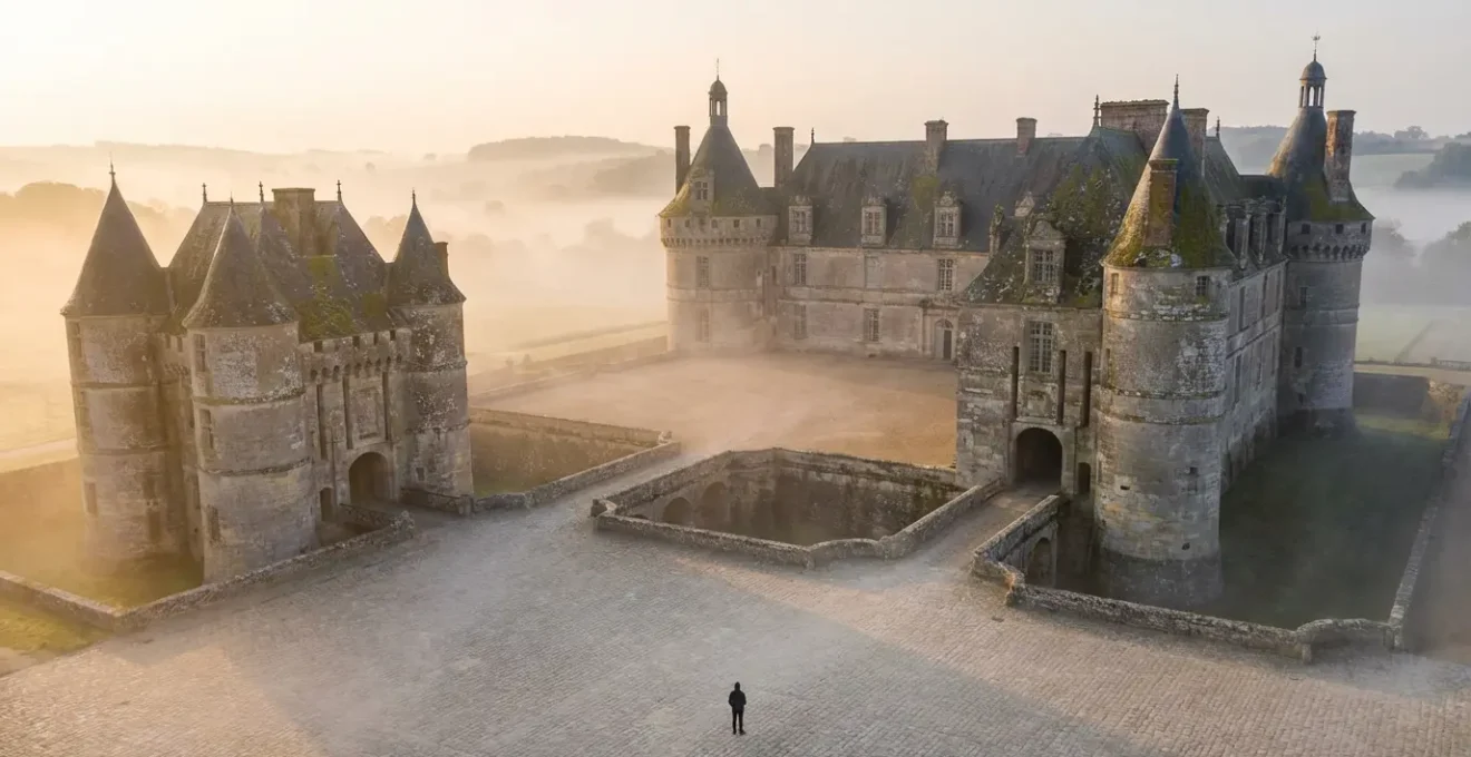 Château français majestueux au lever du soleil avec un seul visiteur contemplant l'architecture