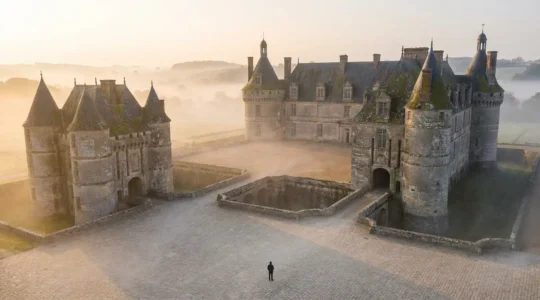 Château français majestueux au lever du soleil avec un seul visiteur contemplant l'architecture